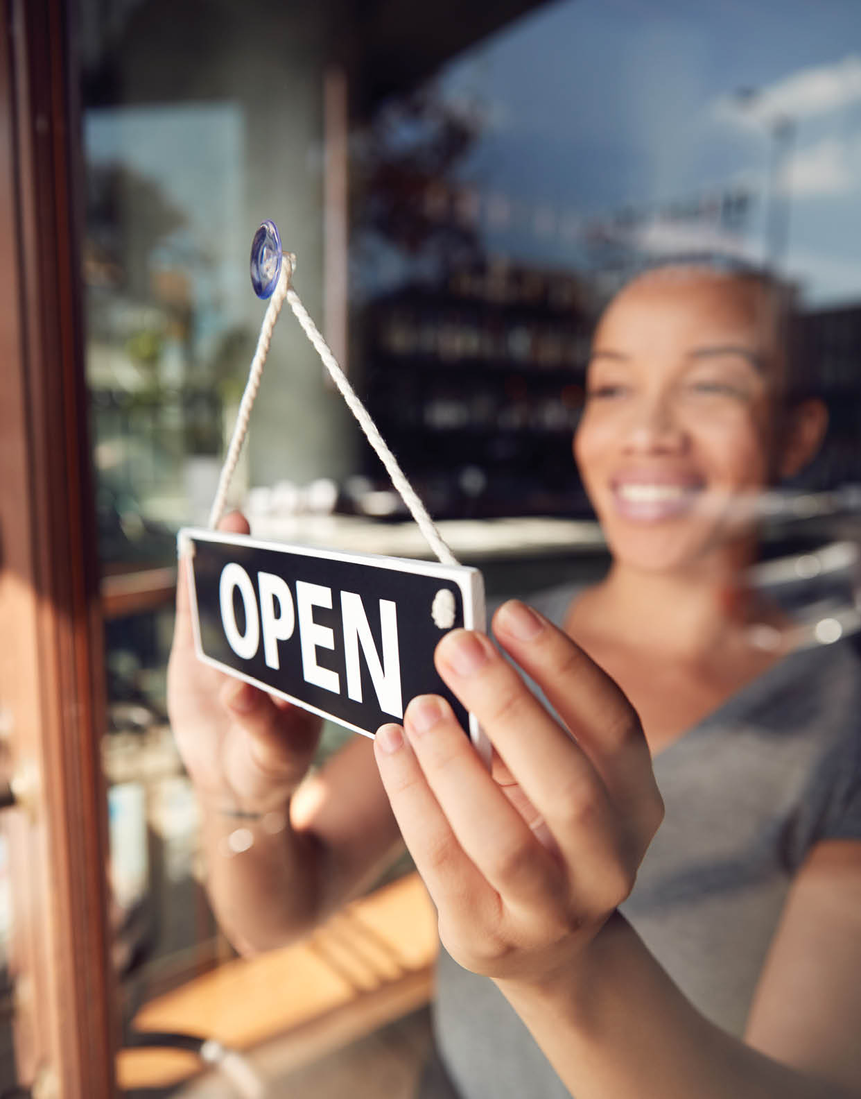 Female Owner Of Start Up Coffee Shop Or Restaurant Turning Round Open Sign On Door