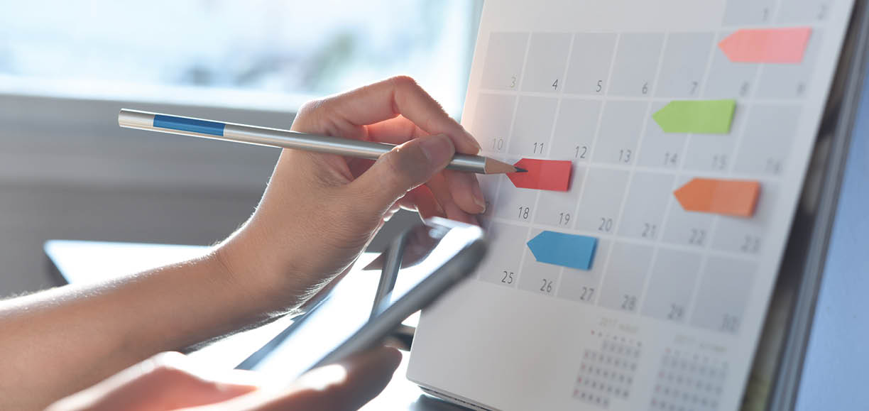 2023 Event planner timetable agenda plan on schedule event. Business woman checking planner on mobile phone, taking note on calendar desk on office table. Calendar event plan, work planning