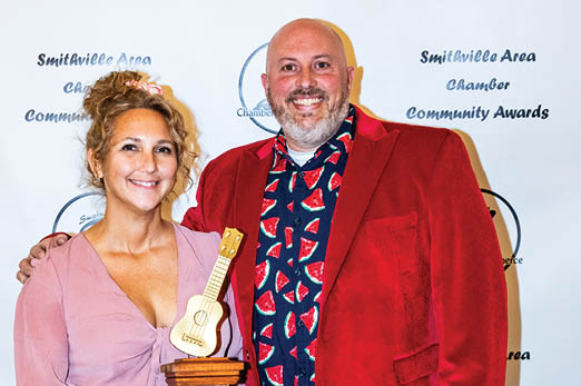 A man and woman pose for a photo, the woman holding a trophy. AI generated content