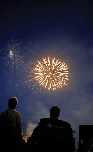 People are sitting in chairs and watching a fireworks display. AI generated content