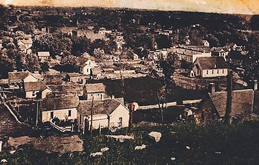 A black and white photo of a small town with a church, houses, and a barn. AI generated content