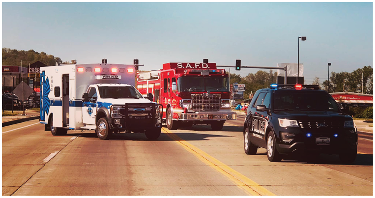 Two emergency vehicles, a fire truck and an ambulance, are driving down a road. AI generated content