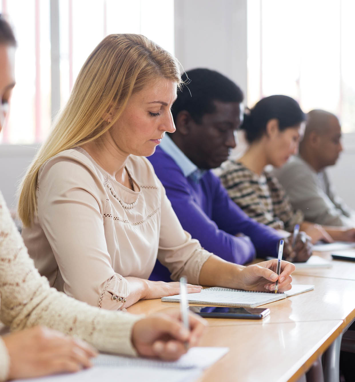 Interested woman sitting on lesson in school auditorium. Adult learning and education concept