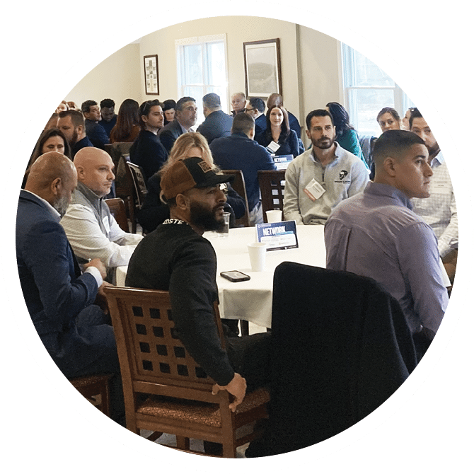 A group of people are sitting around a table, engaged in a meeting. There are several chairs, a dining table, and a cell phone on the table. The people are wearing ties, indicating a formal setting. AI generated content