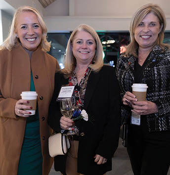 Three women are standing together, holding coffee cups. They are all smiling and appear to be enjoying their time. AI generated content