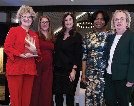 Four women in red and black posing for a photo. AI generated content