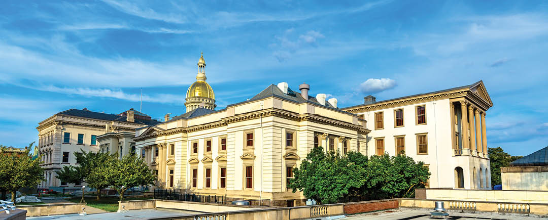 A historic building with classical architecture and a golden dome is set against a bright blue sky with scattered clouds. Description generated by AI