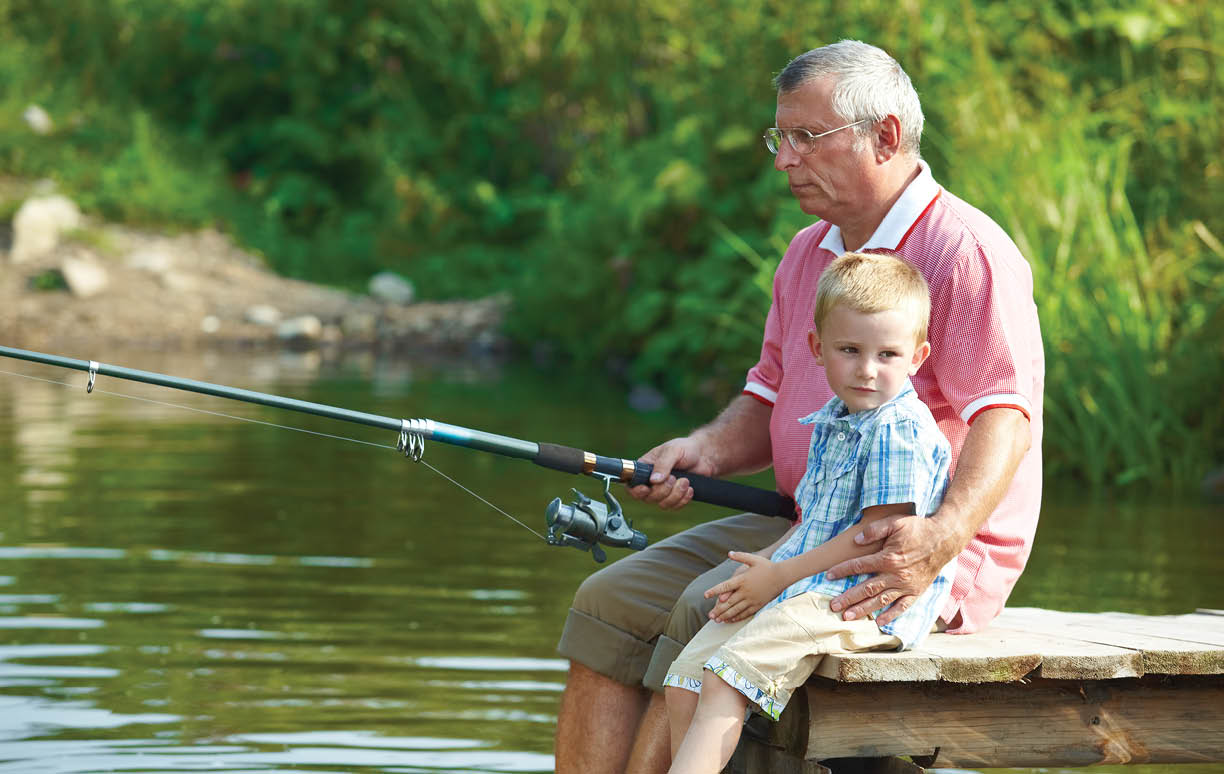 Photo of grandfather and grandson sitting on pontoon and fishing on weekend