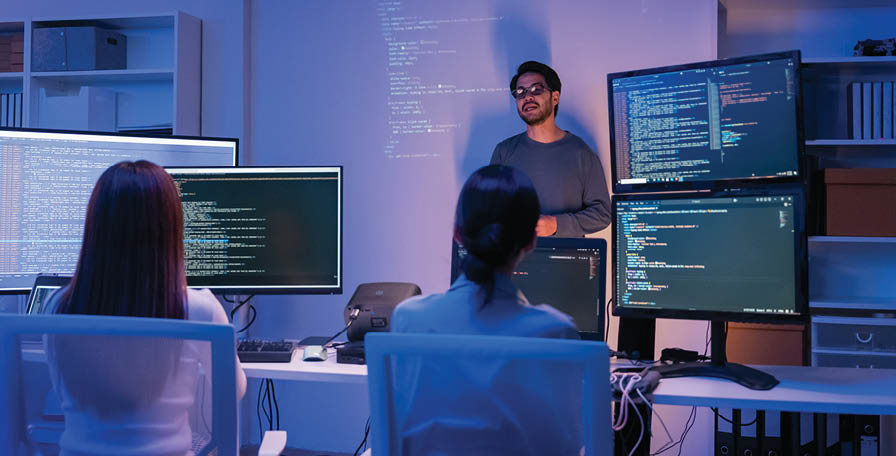 young Asian software development manager leads a late-night office discussion with his executive team, mentoring developers and analyzing source code to guide programming and project development