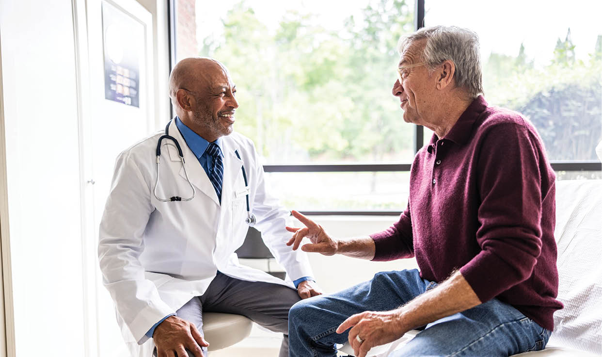 Male doctor talking with senior man in exam room