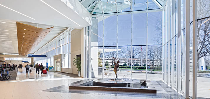 A large glass building with a statue of a nude figure in the center of a fountain. AI generated content