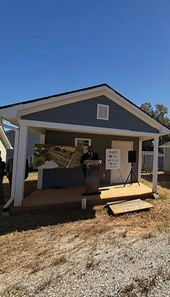 A group of people are standing in a field, looking at a small house. AI generated content