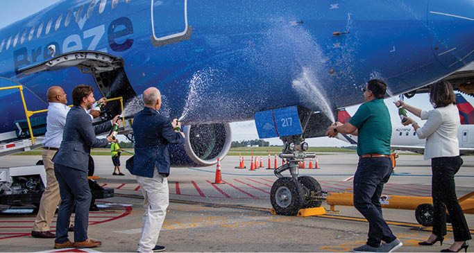 A group of people are spraying a blue airplane with a hose. AI generated content