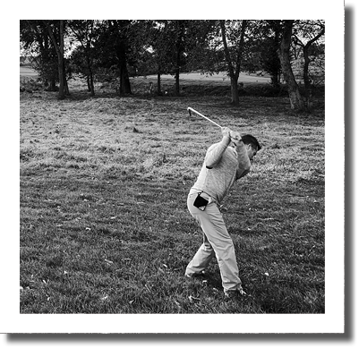 A man is swinging a golf club on a grassy field. AI generated content