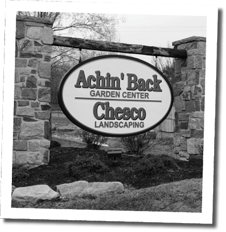A sign for a garden center is displayed in front of a brick wall. AI generated content