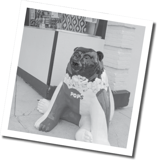 A statue of a dog is sitting on the sidewalk in front of a building. AI generated content
