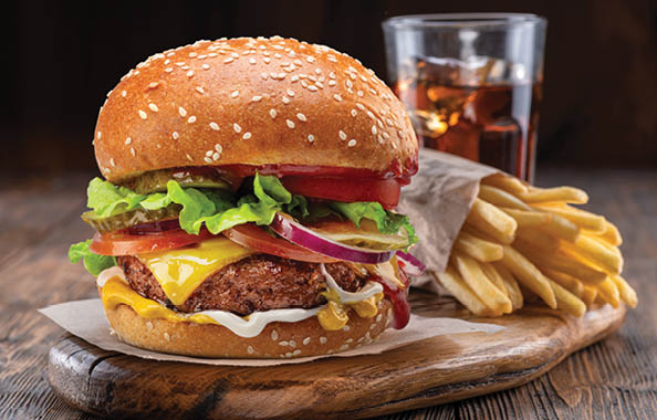 Tasty cheeseburger or hamburger, glass of cola and french fries on wooden tray close-up.