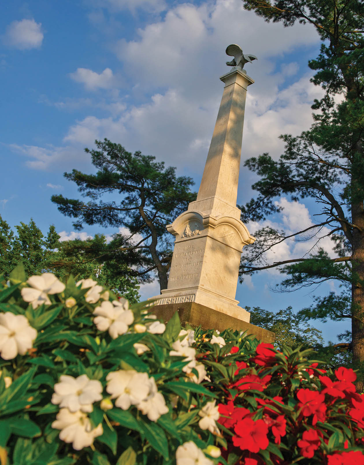 A white and red flower bed with a white statue in the middle. Description generated by AI