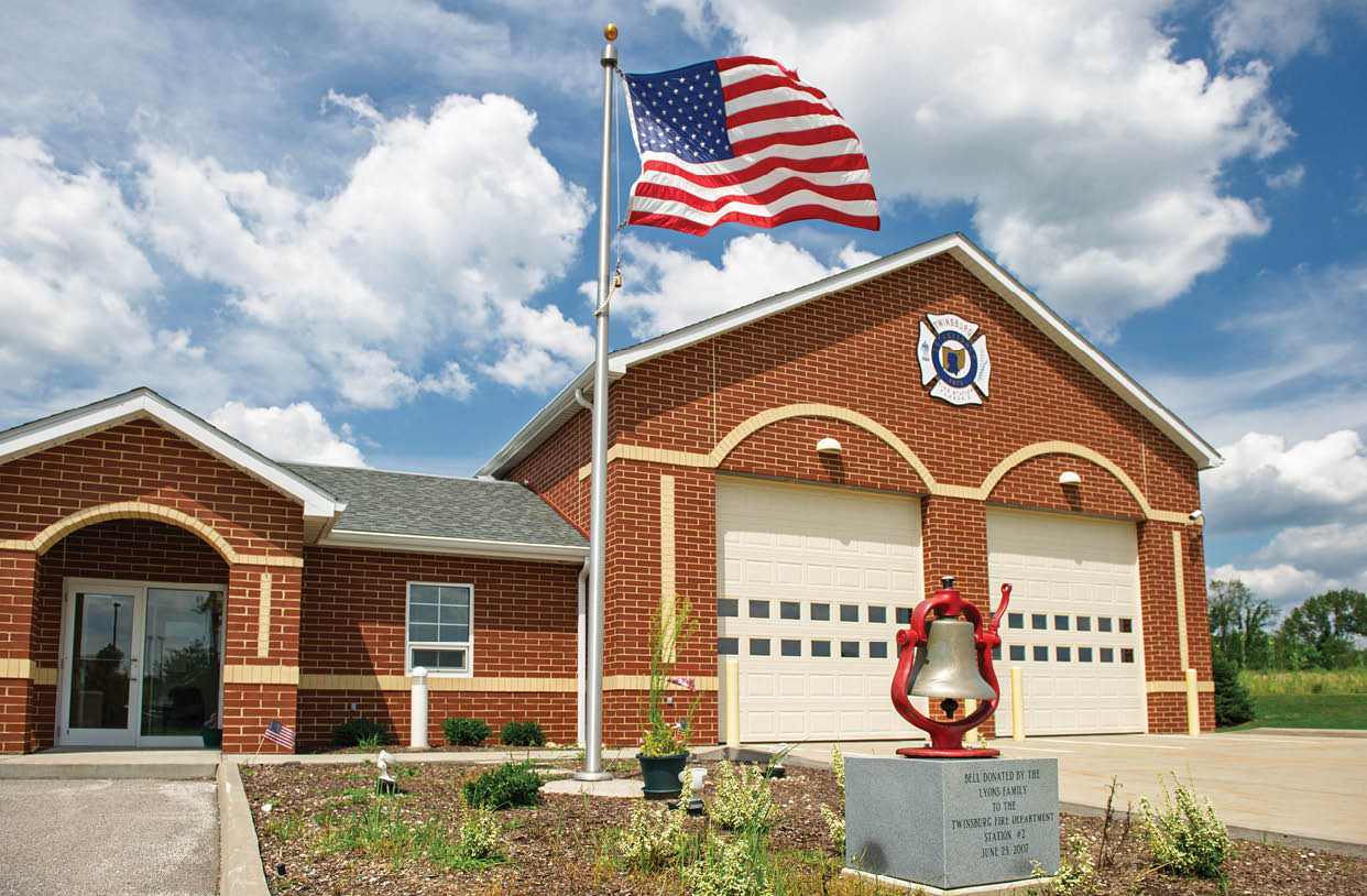 A red fire hydrant is in front of a brick building. Description generated by AI