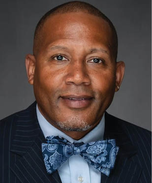 A man wearing a suit and a blue bow tie. Description generated by AI