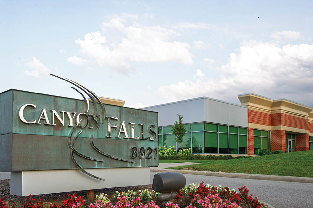 A sign for Canon Falls is in front of a building. Description generated by AI