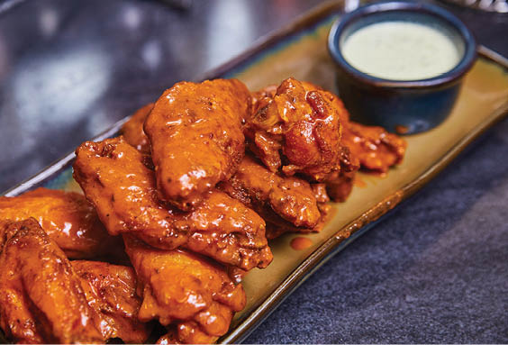 A plate of chicken wings with a dipping sauce. Description generated by AI
