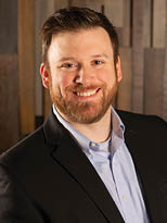 A man wearing a suit and tie smiling. Description generated by AI