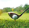 Golf ball and golf club in a beautiful golf course at sunset background. Collection of golf equipment resting on green grass with green background