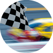 race car blurred on track against rail, checkered flag in foreground, no people, sunny day, car in motion