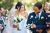 Guests throwing confetti over bride and groom as they walk past after their wedding ceremony. Joyful young couple celebrating their wedding day