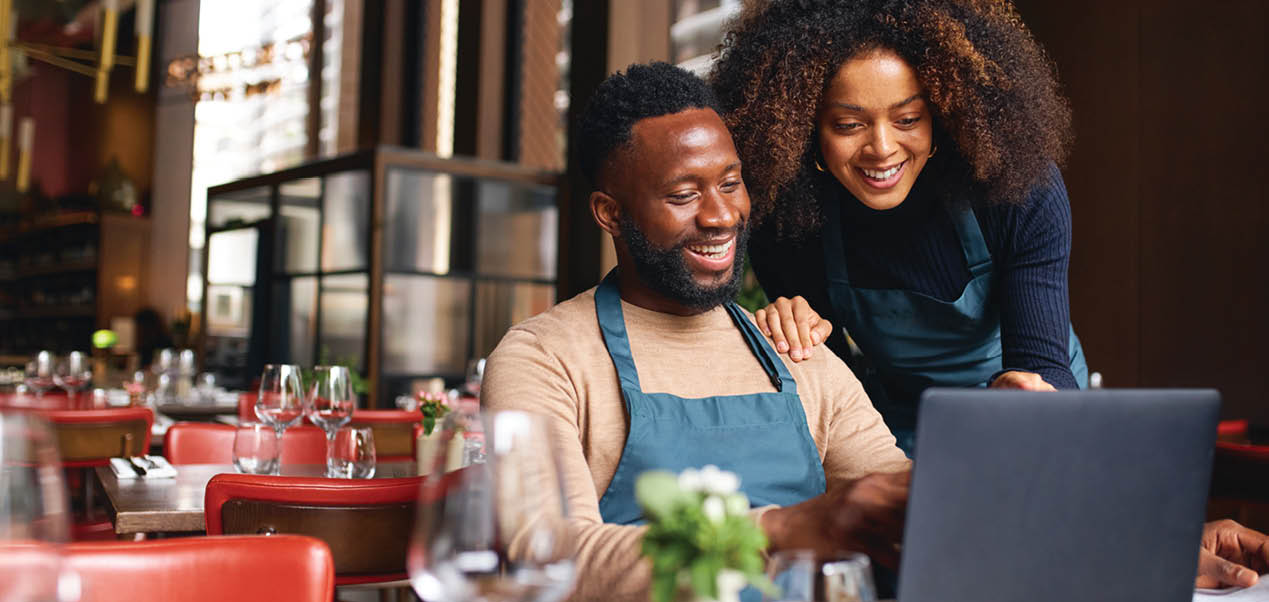 Small business owners using laptop in restaurant