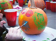 A little girl paints a pumpkin for Halloween