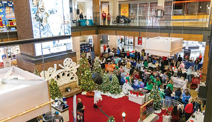 A large group of people are in a building with Christmas trees. Description generated by AI