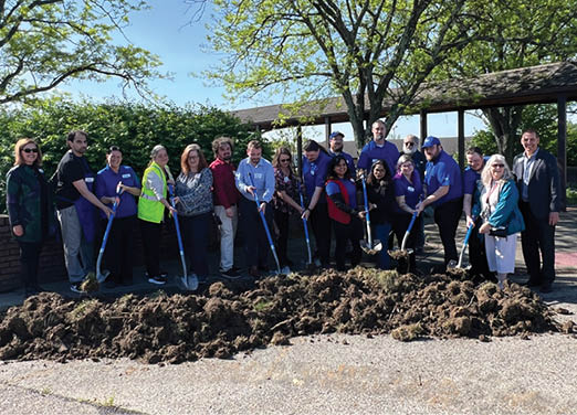 A group of people are standing around a pile of dirt. Description generated by AI