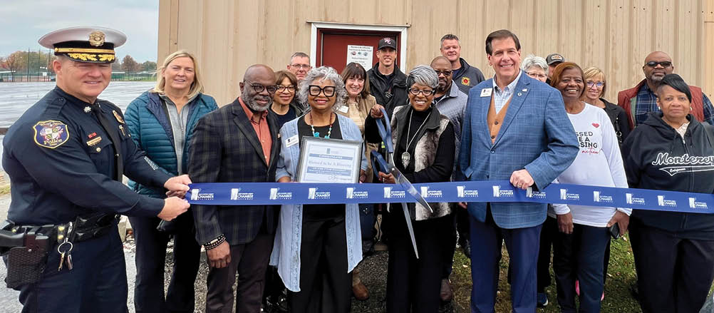 A group of people are standing in front of a building, posing for a photo. They are wearing suits and ties, and some are holding a ribbon. The people are of various ages and genders, and they are all smiling for the camera. AI generated content