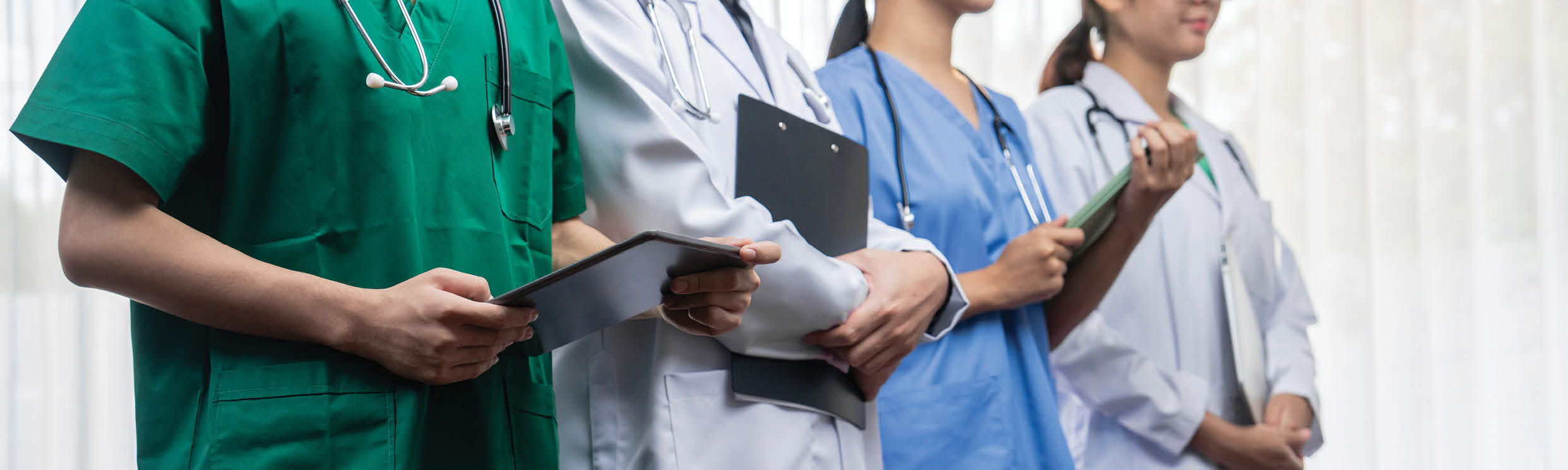 A group of doctors wearing green, blue, and black uniforms. Description generated by AI