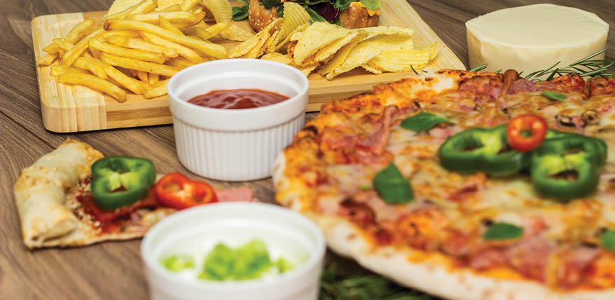 Pepperoni pizza and pizza Capricciosa with mozzarella cheese, ham, tomato sauce, salami, mushroom, pepper, spices and fresh basil. Hamburger with fries and fresh salad. Nacho and potato chips. On wooden table background
