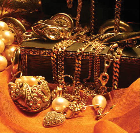 Jewelry laying over a wooden, indian jewelry box on orange chiffon.