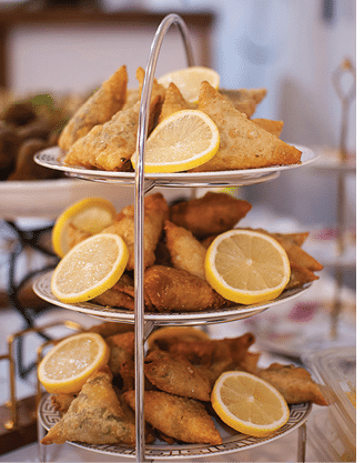 A silver tray holds a variety of food items, including lemon wedges and other treats. AI generated content
