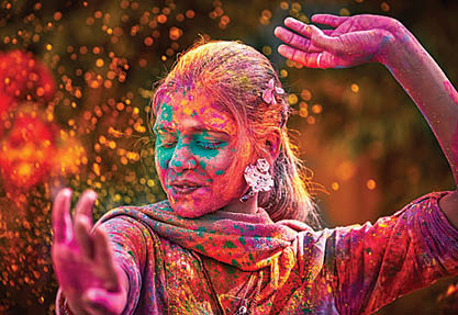 Portrait Of Young Indian Woman With Colored Face Dancing During Holi
