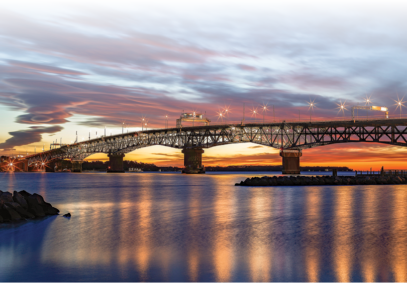 A bridge over water at sunset. Description generated by AI