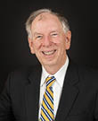 A man wearing a suit and tie with a yellow tie. Description generated by AI