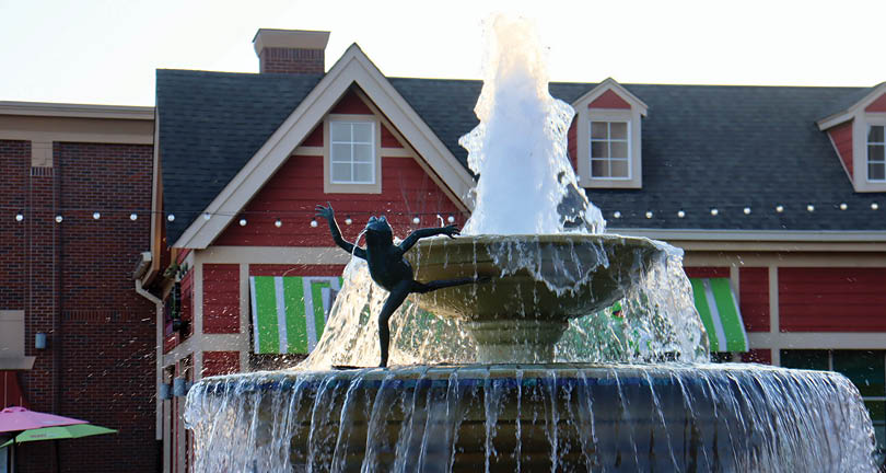A statue of a woman is in the middle of a fountain. Description generated by AI