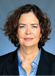 A woman wearing a blue shirt and black jacket. Description generated by AI