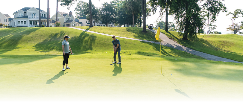Two men playing golf on a green course. Description generated by AI