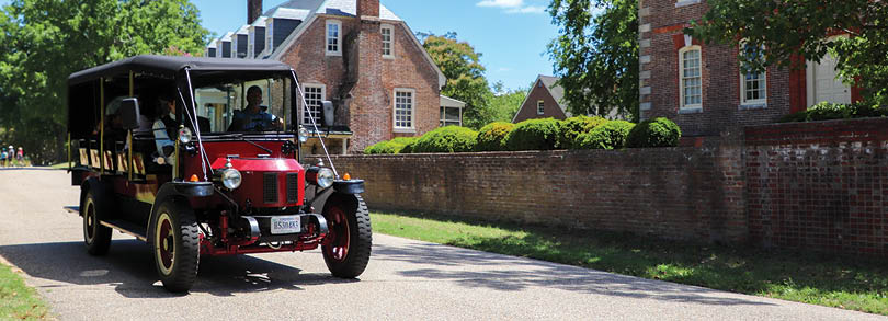 A red and black antique truck driving down a street. Description generated by AI