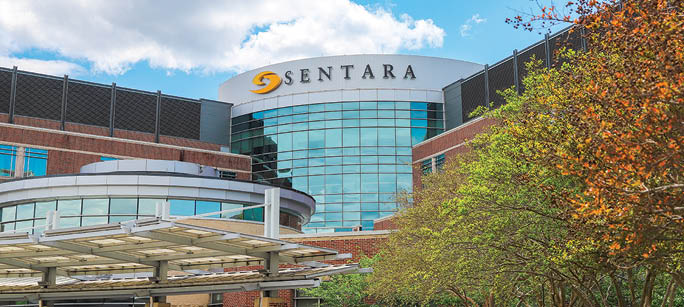 A large building with a white sign that says “Sentara" on it. Description generated by AI