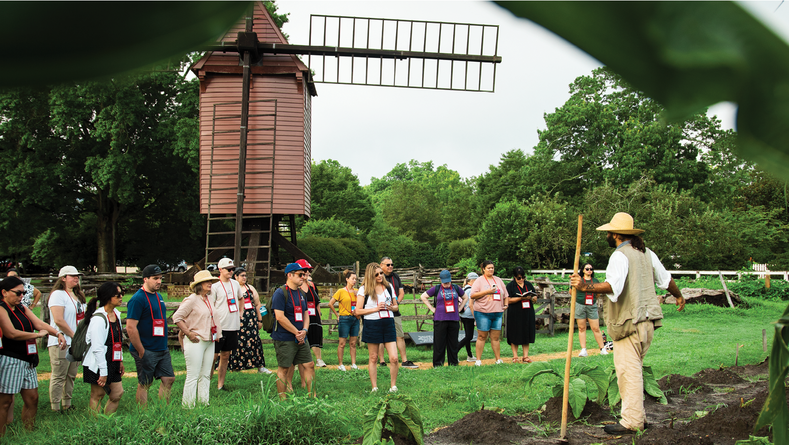 A man is holding a stick in a field with a group of people. Description generated by AI