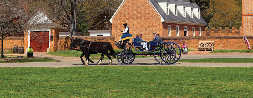 A horse-drawn carriage with two horses and two people riding in it. Description generated by AI