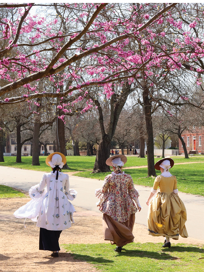 A group of women walking in a park with pink flowers in the background. Description generated by AI